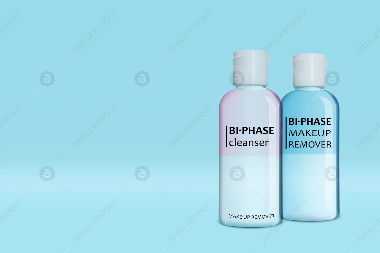 Image of Bottles of bi-phase makeup removers on light blue background, space for text