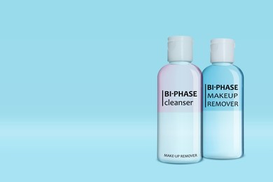 Bottles of bi-phase makeup removers on light blue background, space for text