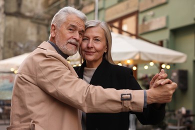 Photo of Affectionate senior couple dancing together on city street