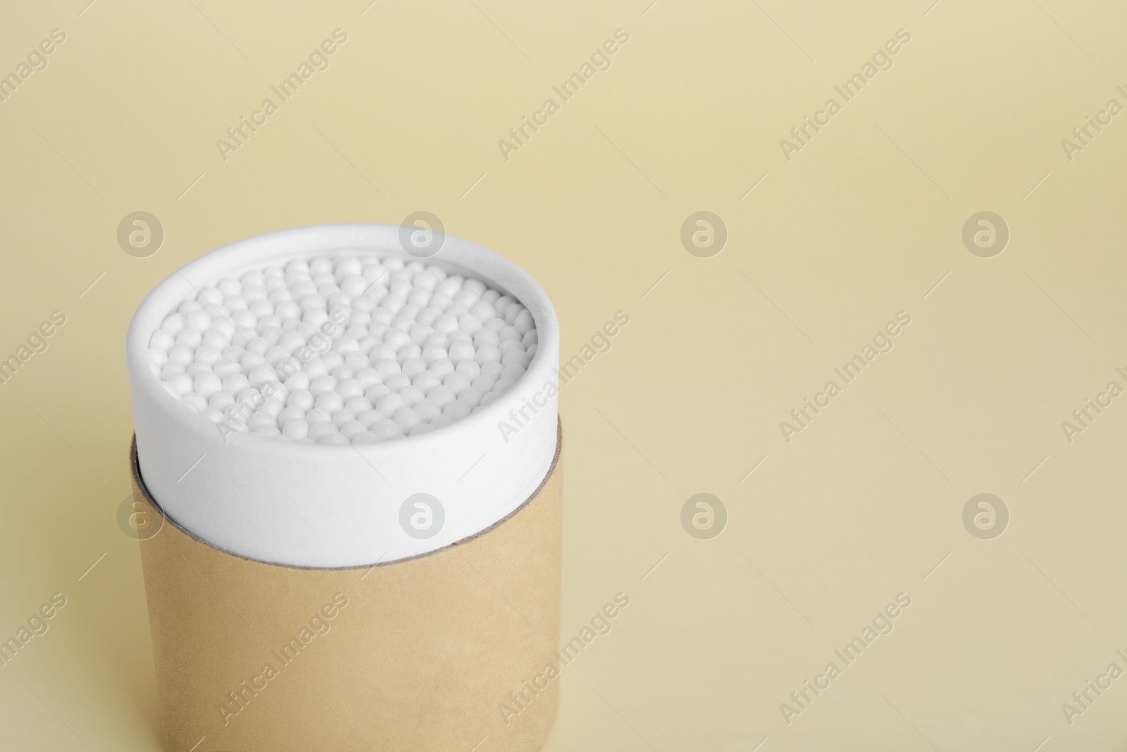 Photo of Container with new cotton buds on beige background. Space for text