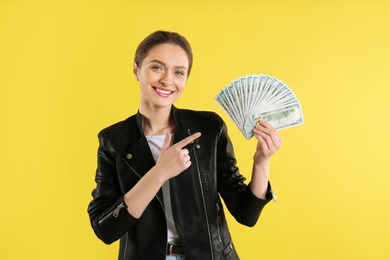 Young woman with money on yellow background