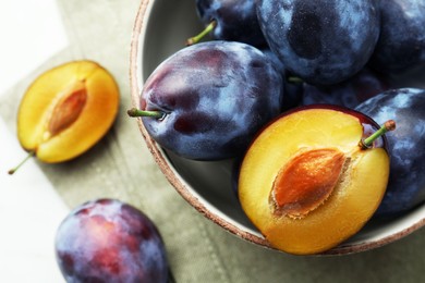 Photo of Tasty ripe plums in bowl on table, closeup