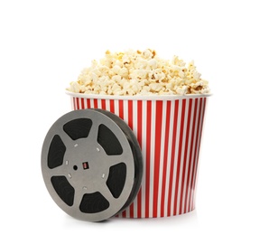 Photo of Bucket with tasty popcorn and film reel on white background