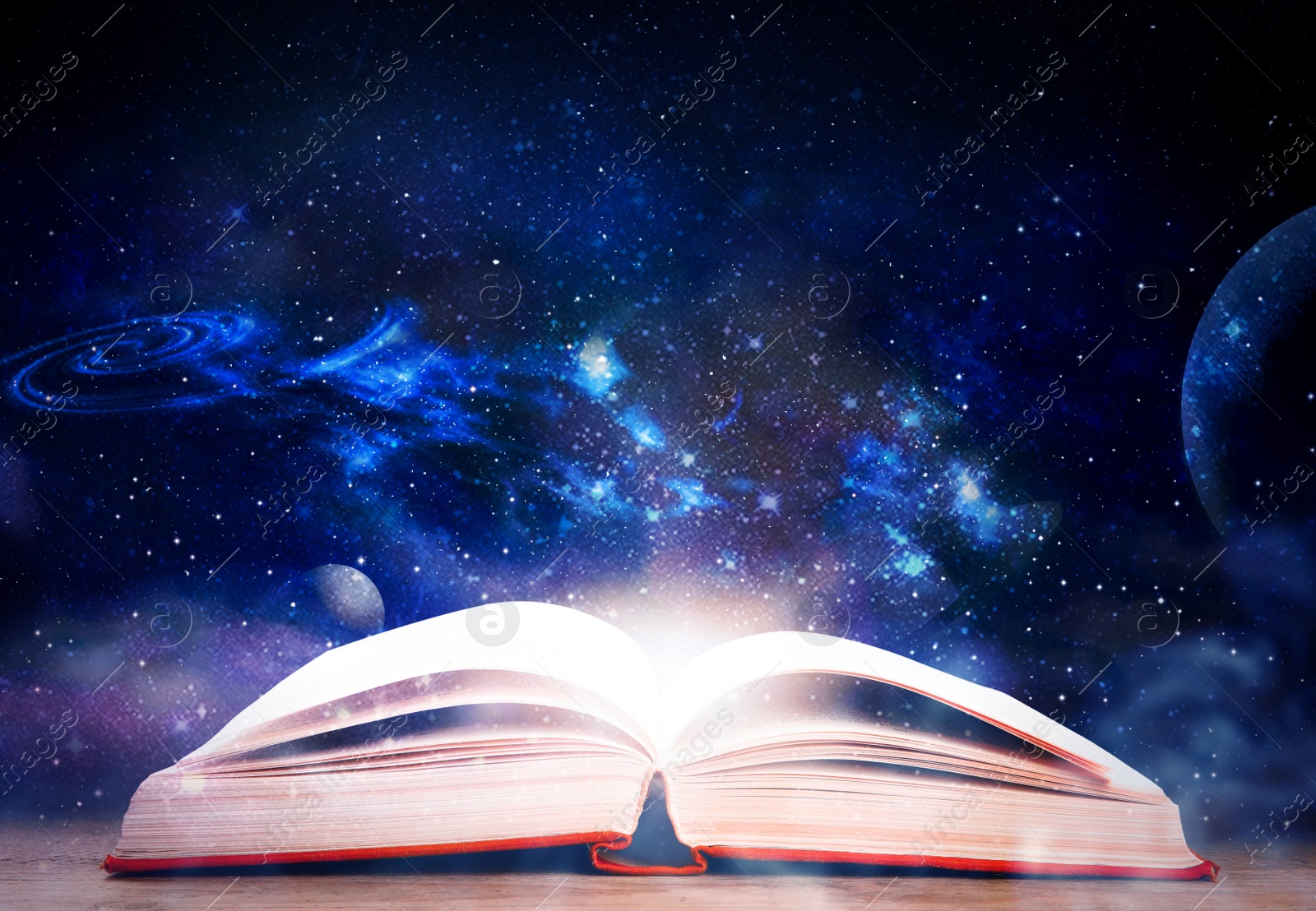 Image of Wooden table with open book and beautiful universe on background