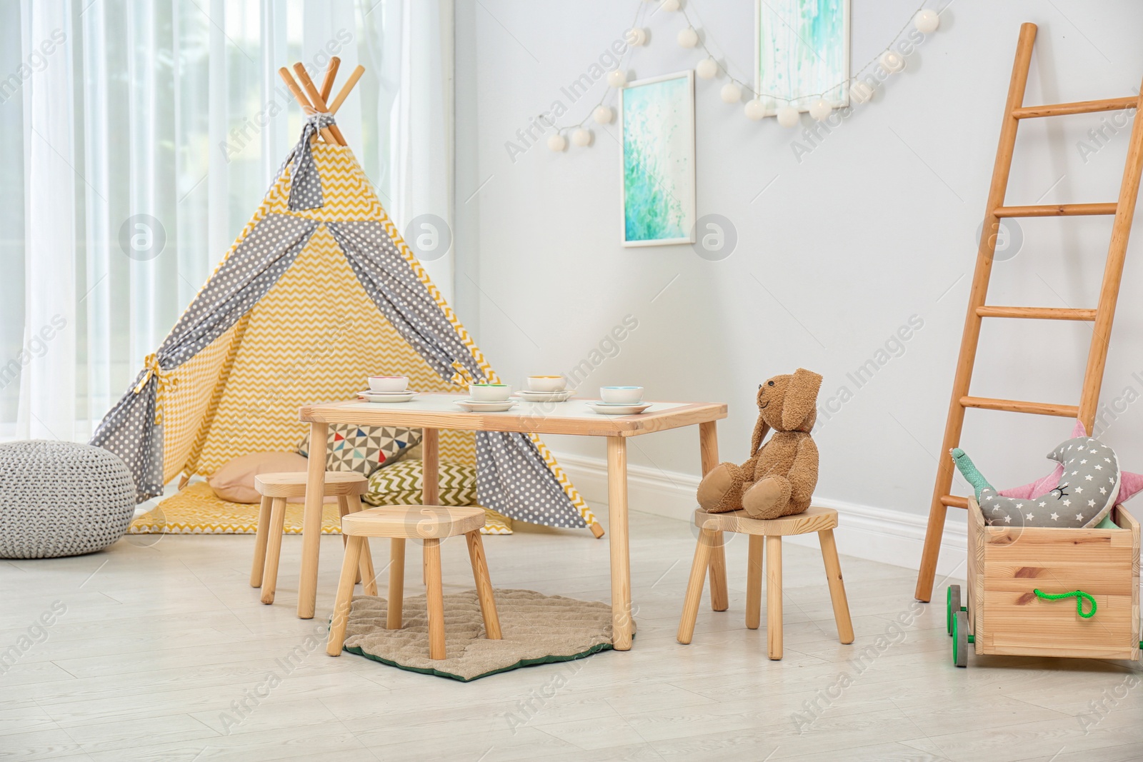 Photo of Cozy kids room interior with table, play tent and toys