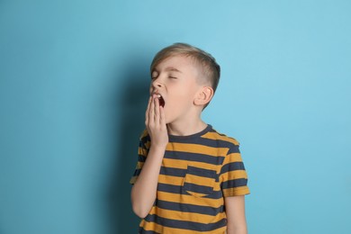 Photo of Portrait of sleepy boy yawning on turquoise background
