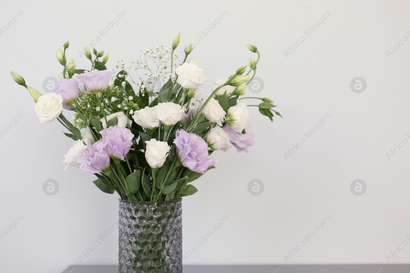 Photo of Bouquet of beautiful Eustoma flowers on light background, closeup. Space for text