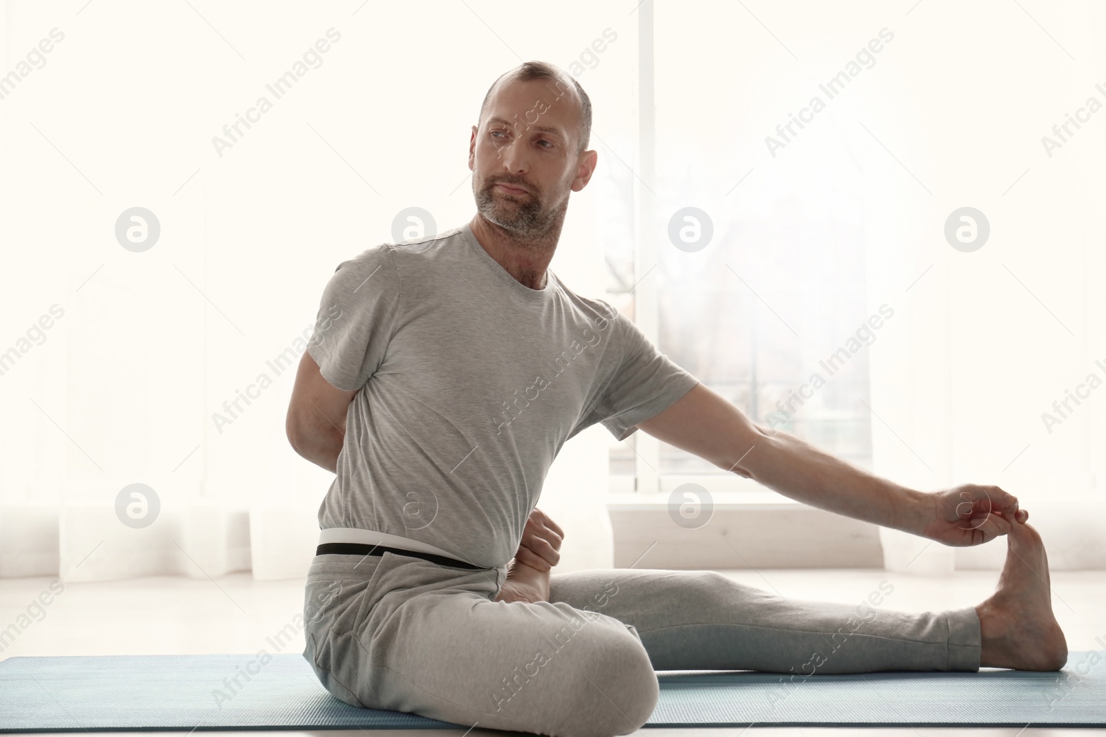Photo of Sporty man practicing yoga indoors