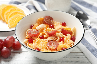 Photo of Corn flakes with berries on white wooden table, closeup. Healthy breakfast