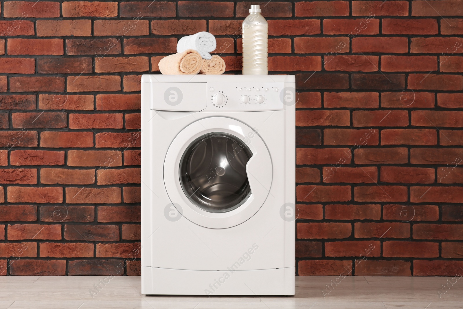 Photo of Washing machine, terry towels and bottle indoors. Laundry room interior design