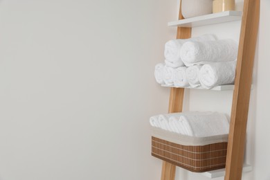 Photo of Soft towels on decorative ladder near white wall, space for text