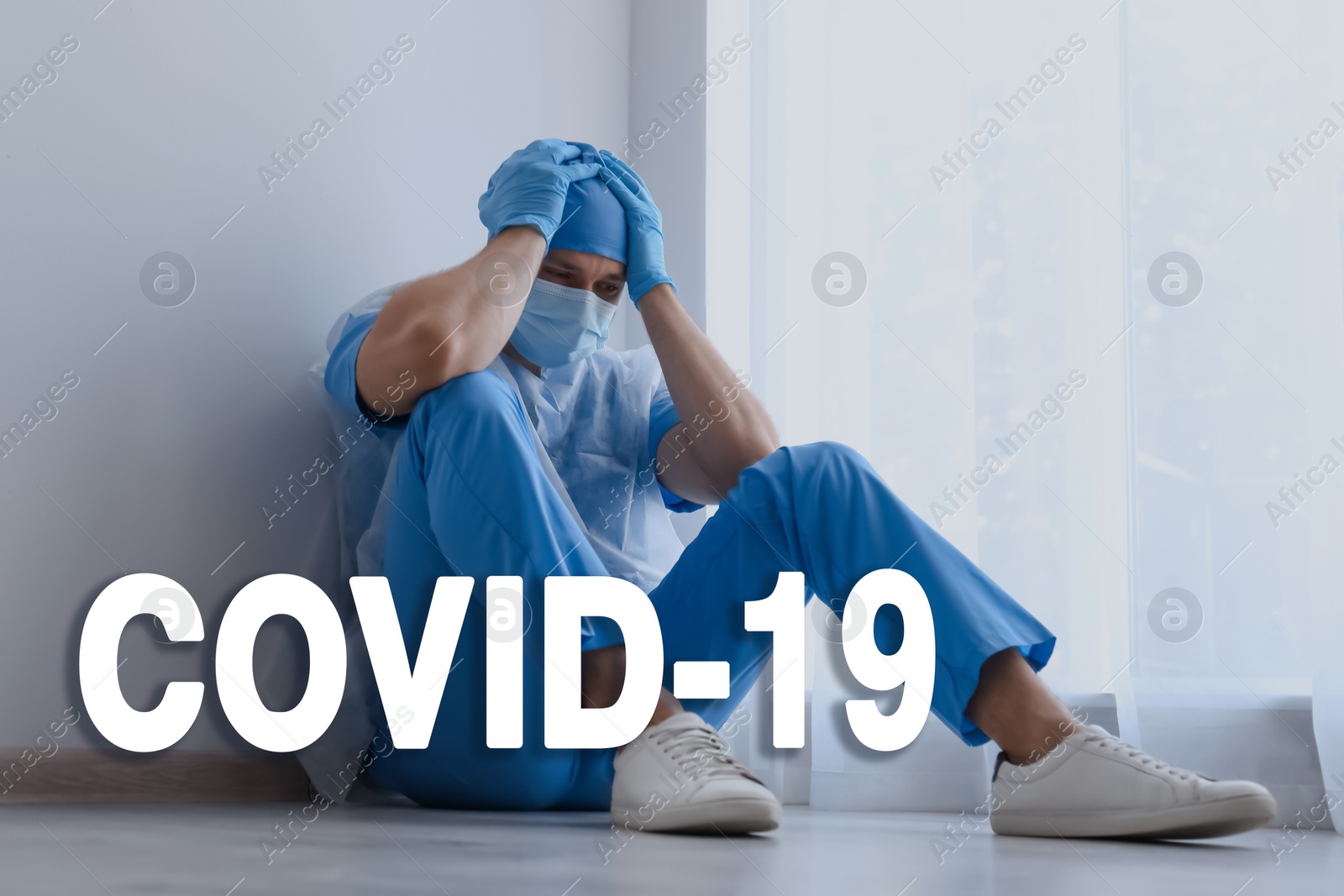 Image of Tired overwhelmed doctor sitting on floor in hospital. Medical system collapse during coronavirus pandemic