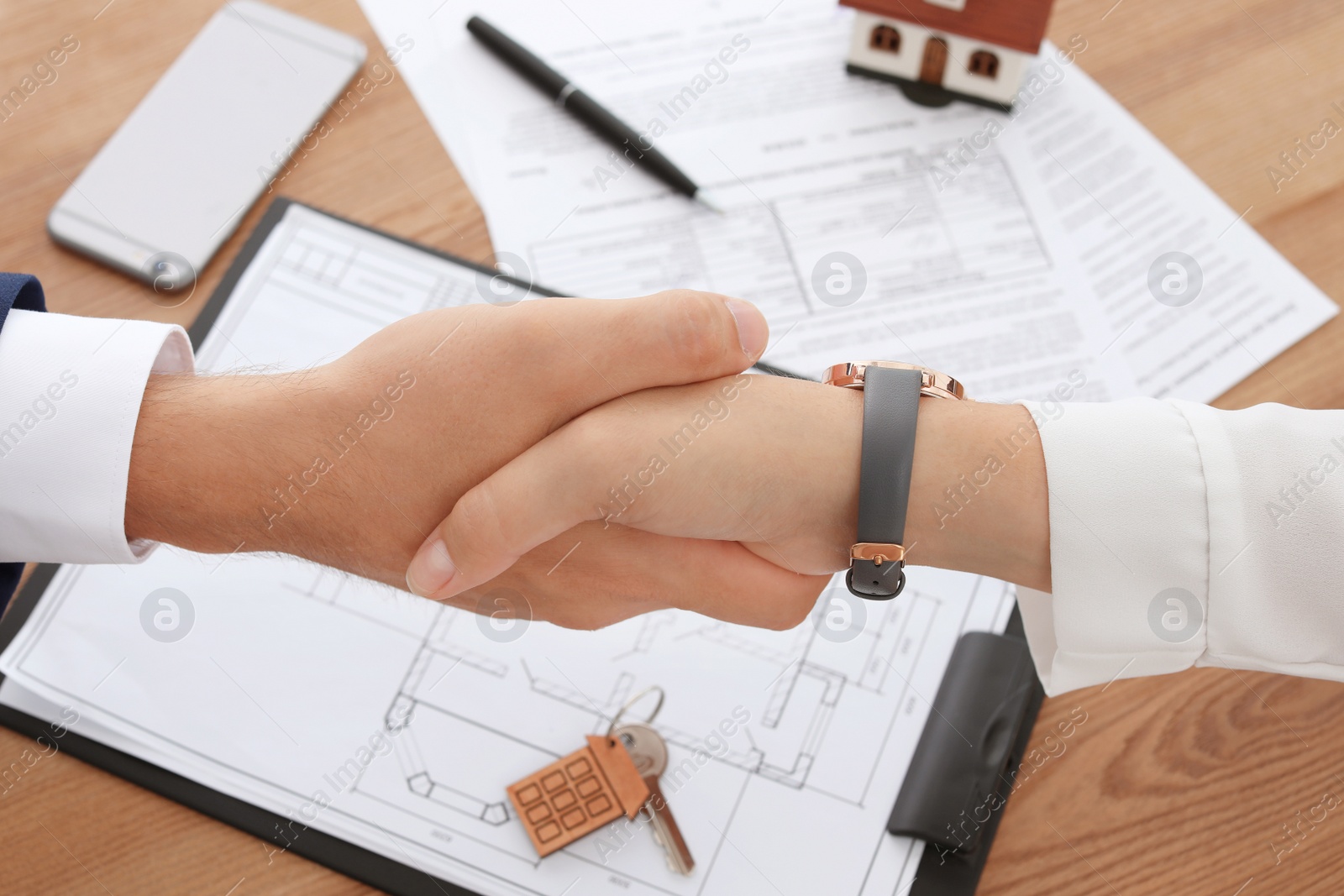 Photo of Woman shaking hands with real estate agent in office, closeup