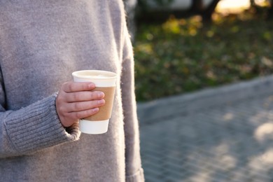 Photo of Coffee to go. Woman holding takeaway cardboard cup on city street, closeup. Space for text