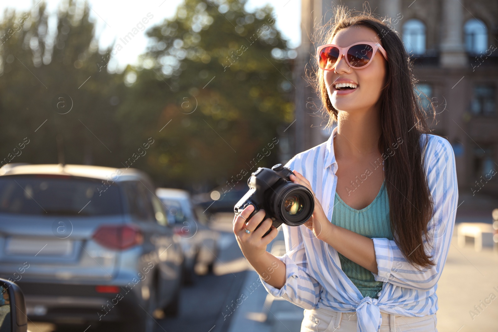 Photo of Young photographer with professional camera outdoors. Space for text