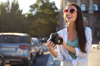 Young photographer with professional camera outdoors. Space for text