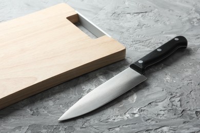 Photo of Knife and wooden board on grey textured table