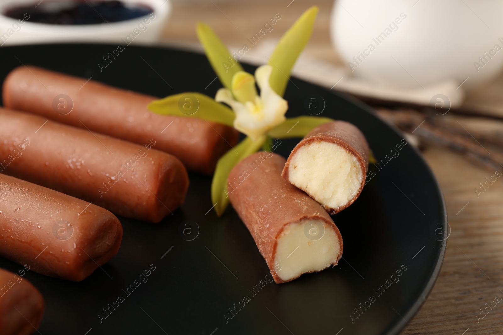 Photo of Glazed vanilla curd cheese bars served on wooden table, closeup