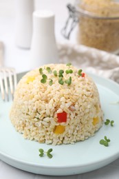 Photo of Delicious bulgur with vegetables and microgreens on table, closeup