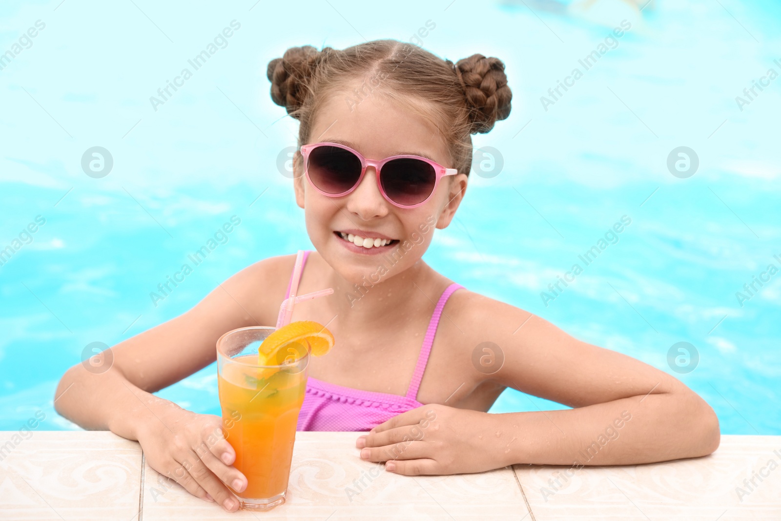 Photo of Little girl with cocktail in pool on sunny day