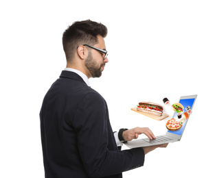 Young man using laptop for ordering food online on white background. Delivery service during quarantine