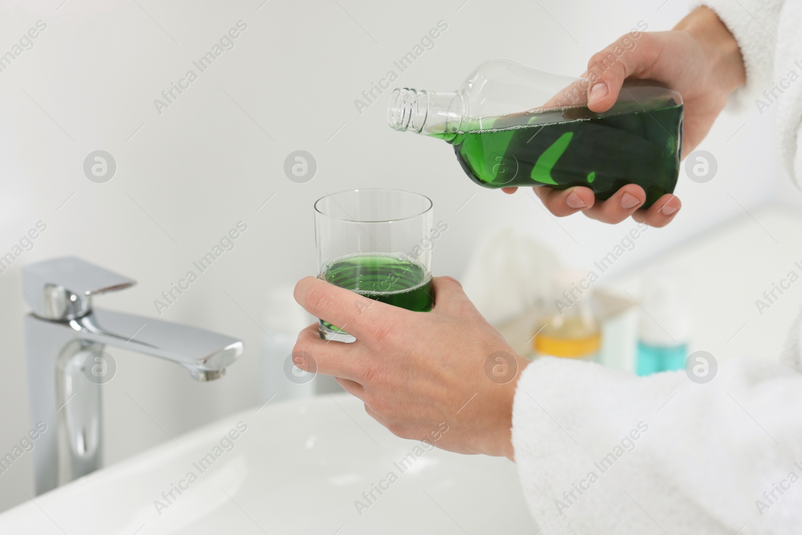 Photo of Young man using mouthwash in bathroom, closeup