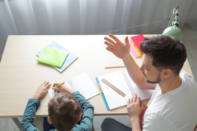 Dad helping his son with school assignment at home, above view