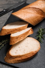 Photo of Cut tasty baguette with thyme on grey table, closeup