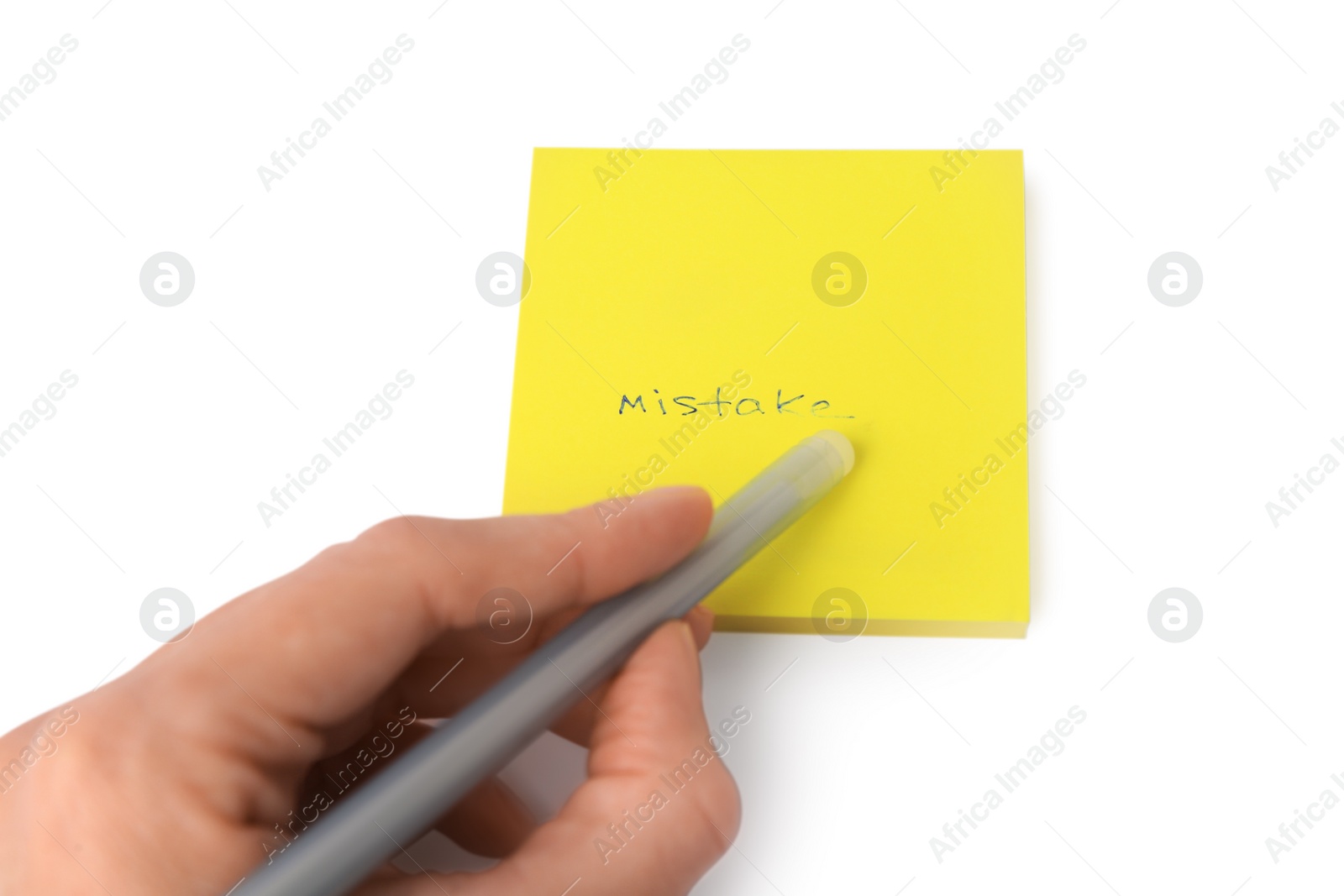 Photo of Child erasing word Mistake written with erasable pen on sticky note against white background, closeup