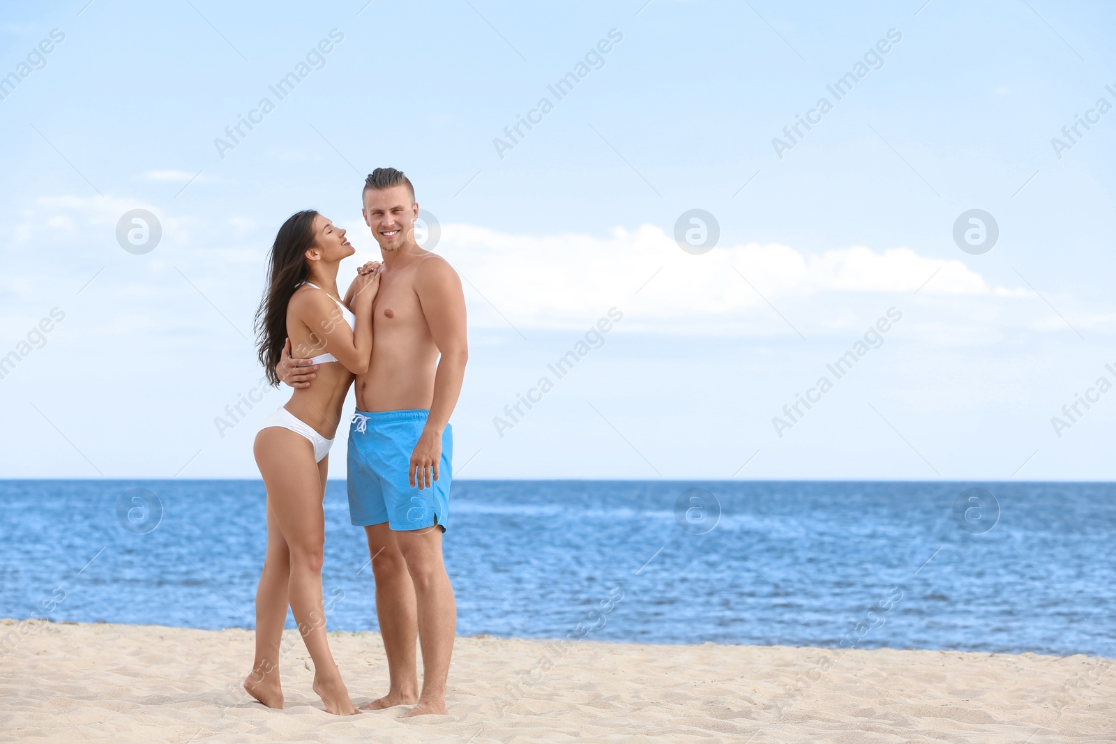 Photo of Young woman in bikini spending time with her boyfriend on beach. Lovely couple