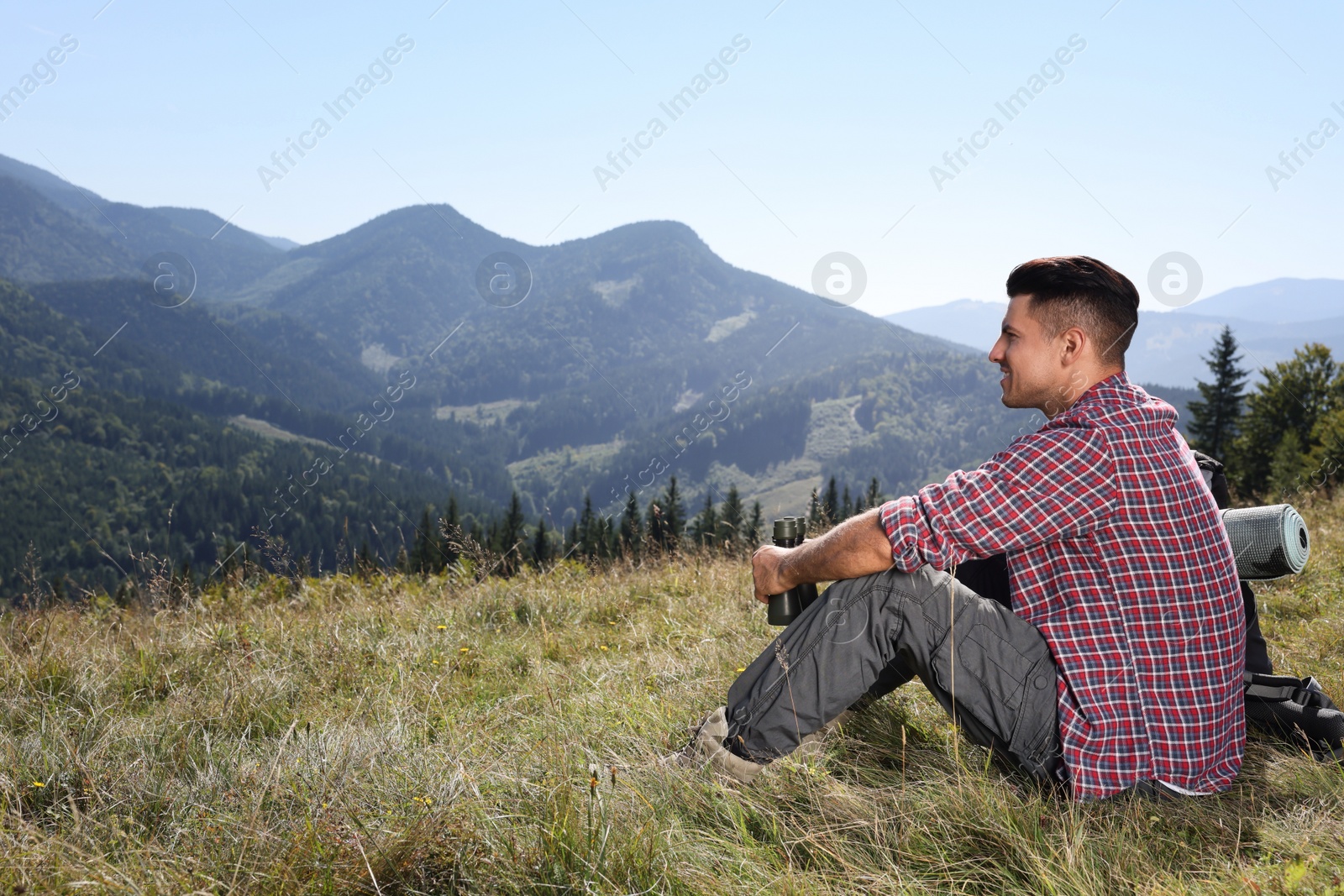 Photo of Tourist with backpack sitting on ground and enjoying view in mountains