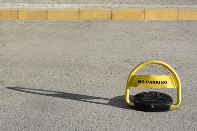 Photo of Parking barrier with No Stopping road sign on asphalt outdoors, space for text