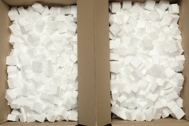 Open cardboard boxes with pieces of polystyrene foam as background, top view