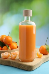 Photo of Delicious tangerine liqueur and fresh fruits on light blue wooden table