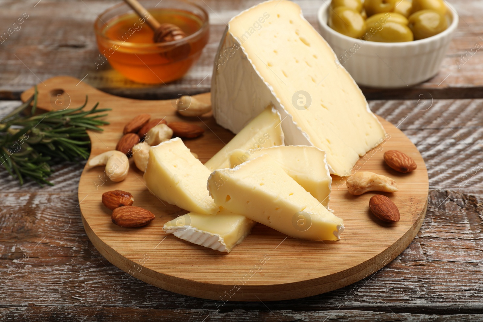 Photo of Tasty Camembert cheese with nuts on wooden table