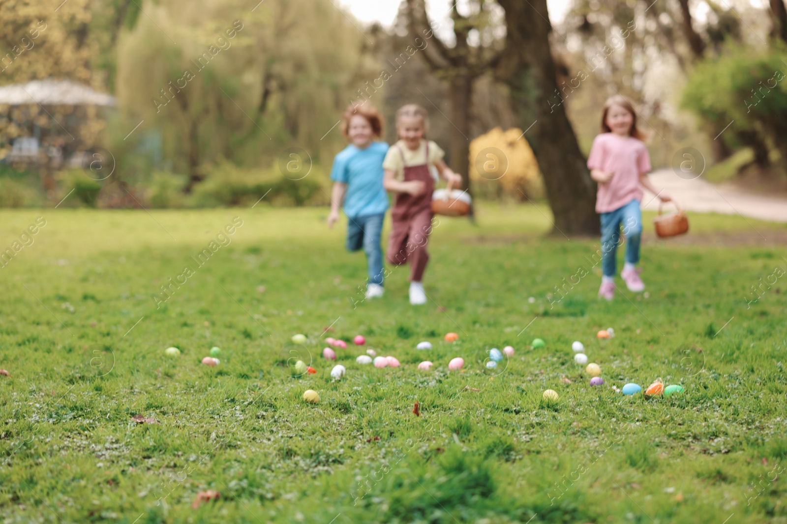 Photo of Easter celebration. Little children hunting eggs outdoors, selective focus