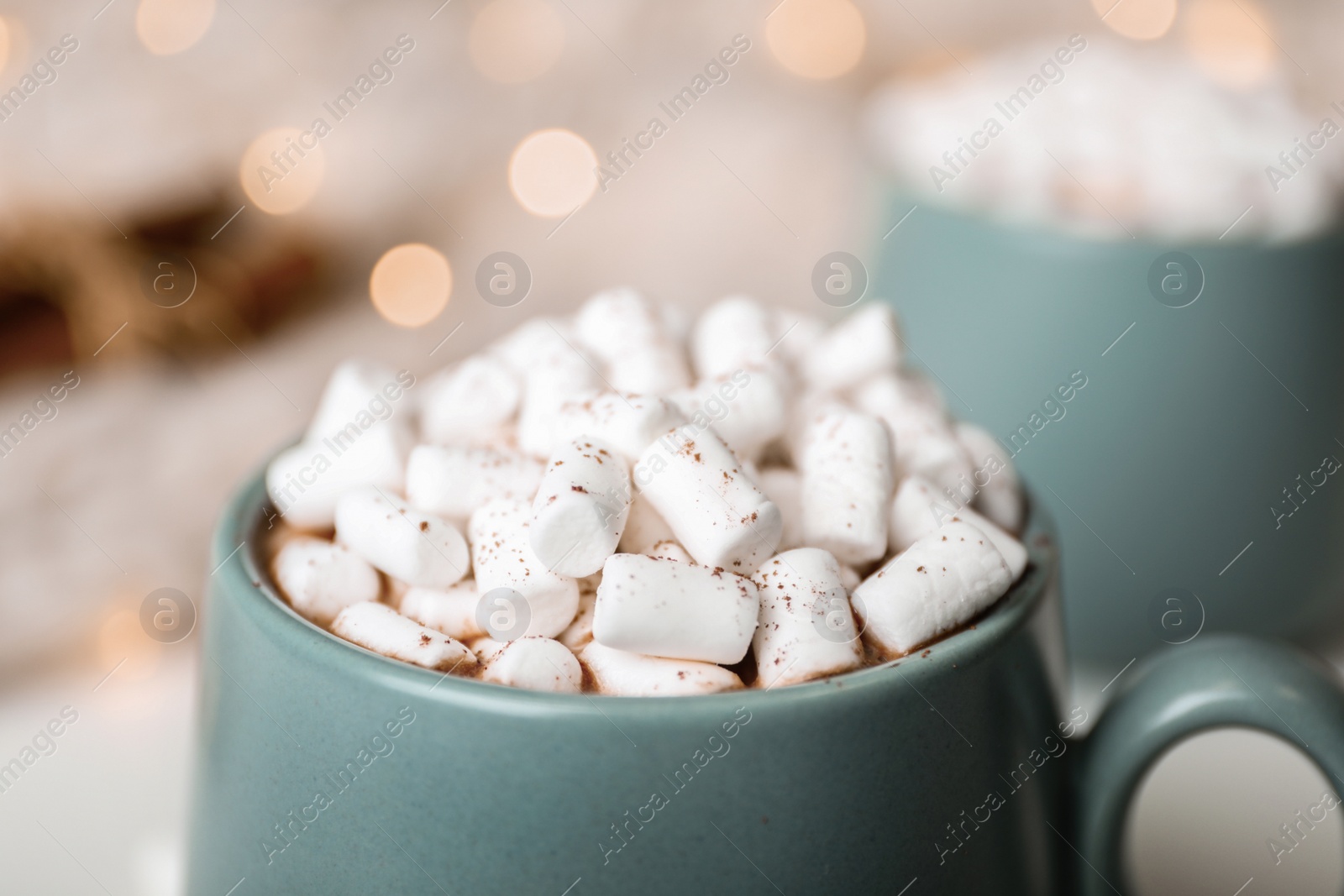 Photo of Delicious cocoa drink with marshmallows on table against blurred lights, closeup