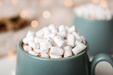 Delicious cocoa drink with marshmallows on table against blurred lights, closeup