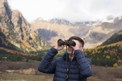 Boy looking through binoculars in beautiful mountains