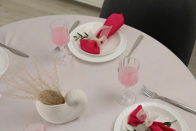 Color accent table setting. Glasses, plates, cutlery and pink napkins on table