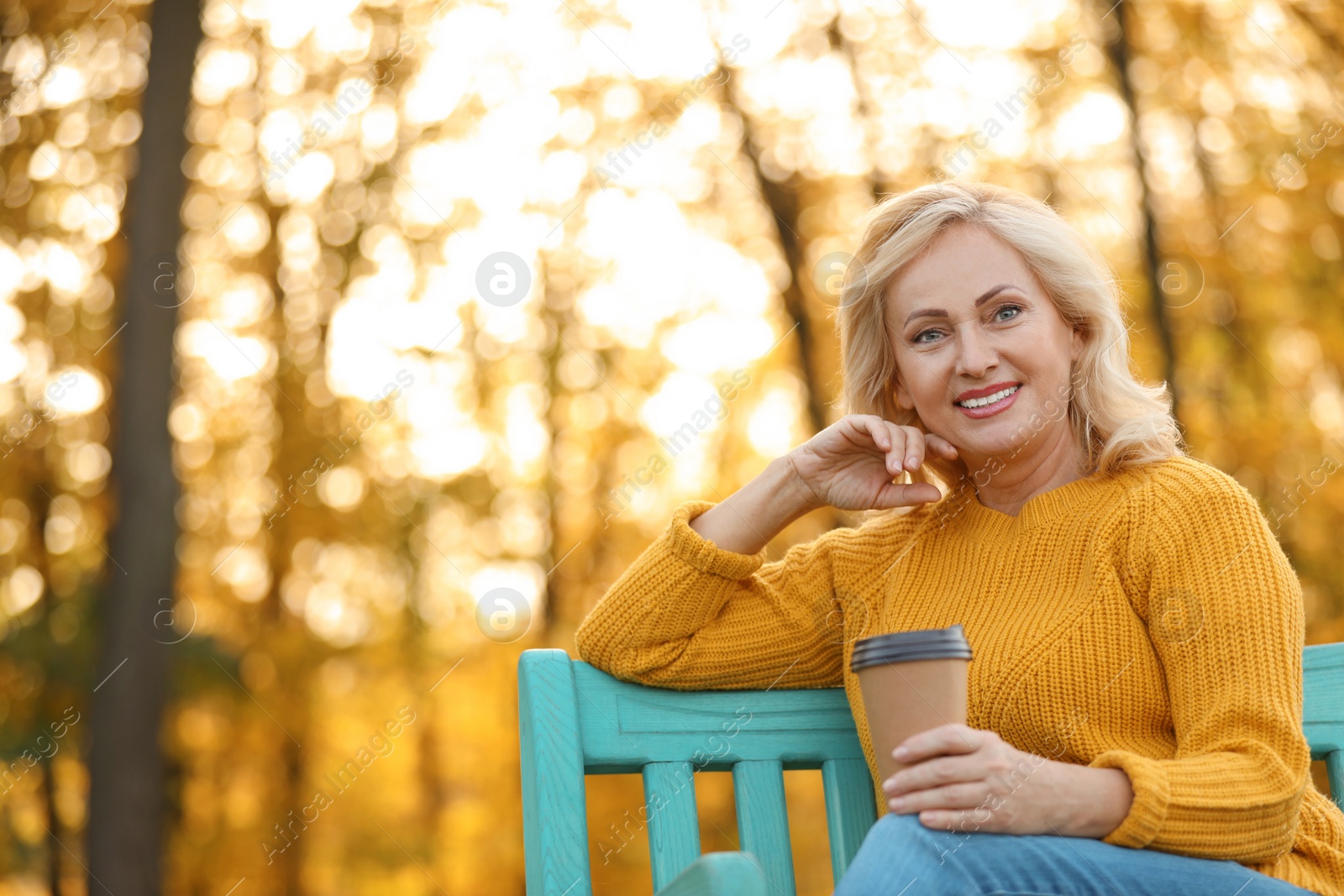 Photo of Beautiful mature woman with cup of coffee on bench in park