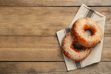 Delicious fresh bagels with sesame seeds on wooden table, top view. Space for text