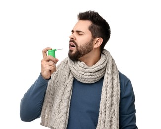 Young man with scarf using throat spray on white background