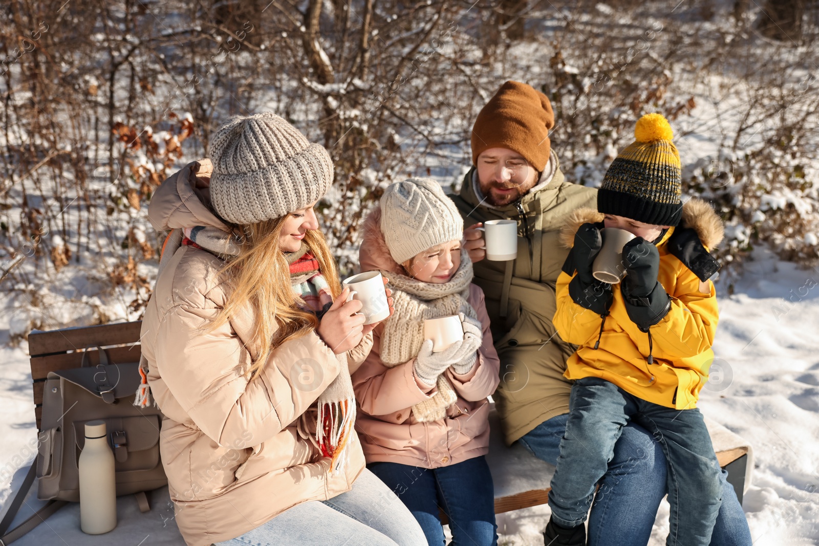 Photo of Family warming themselves with hot tea outdoors on snowy day