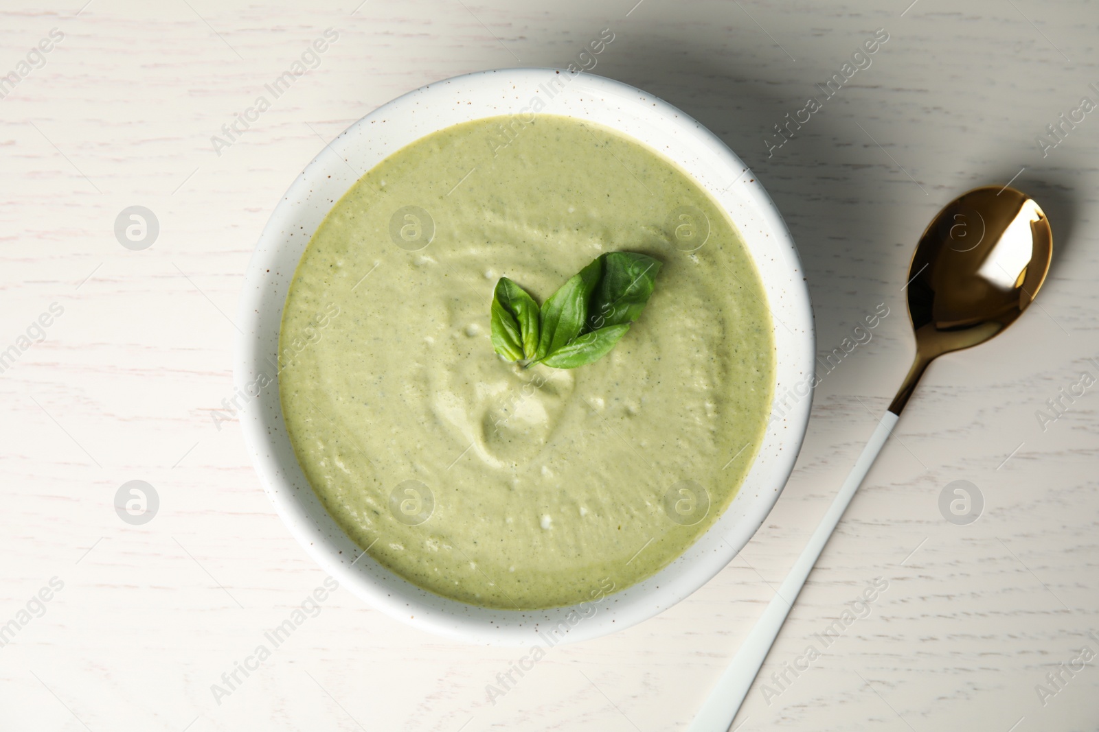 Photo of Delicious broccoli cream soup served on white wooden table, flat lay