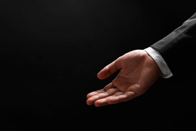 Photo of Man holding something in hand on black background, closeup. Space for text