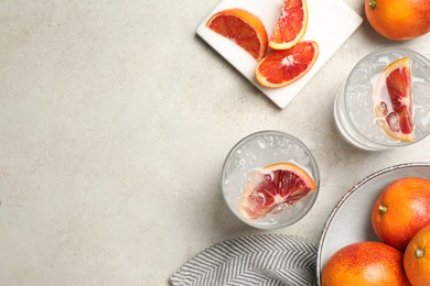 Photo of Delicious refreshing drink with sicilian orange and ice cubes served on light table, flat lay. Space for text