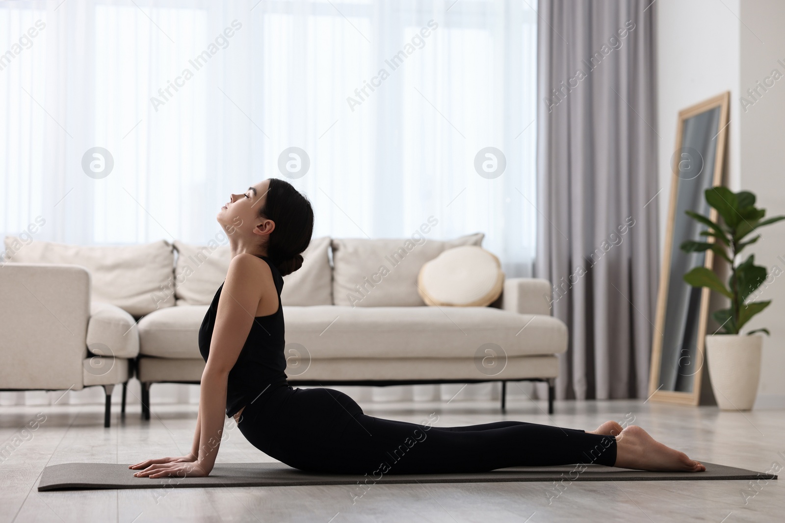 Photo of Girl practicing cobra asana on yoga mat at home. Bhujangasana pose