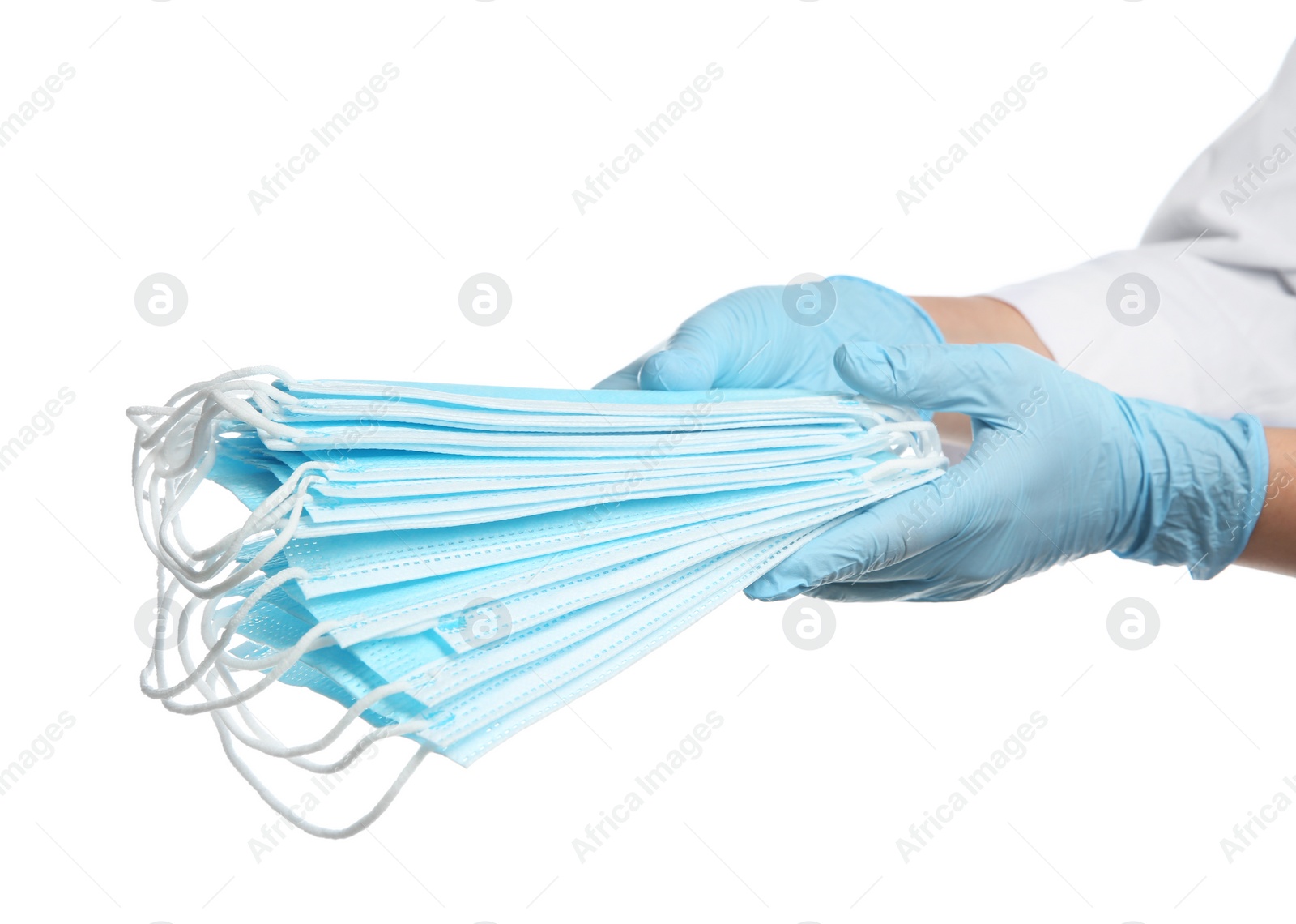 Photo of Doctor in latex gloves holding disposable face masks on white background, closeup. Protective measures during coronavirus quarantine