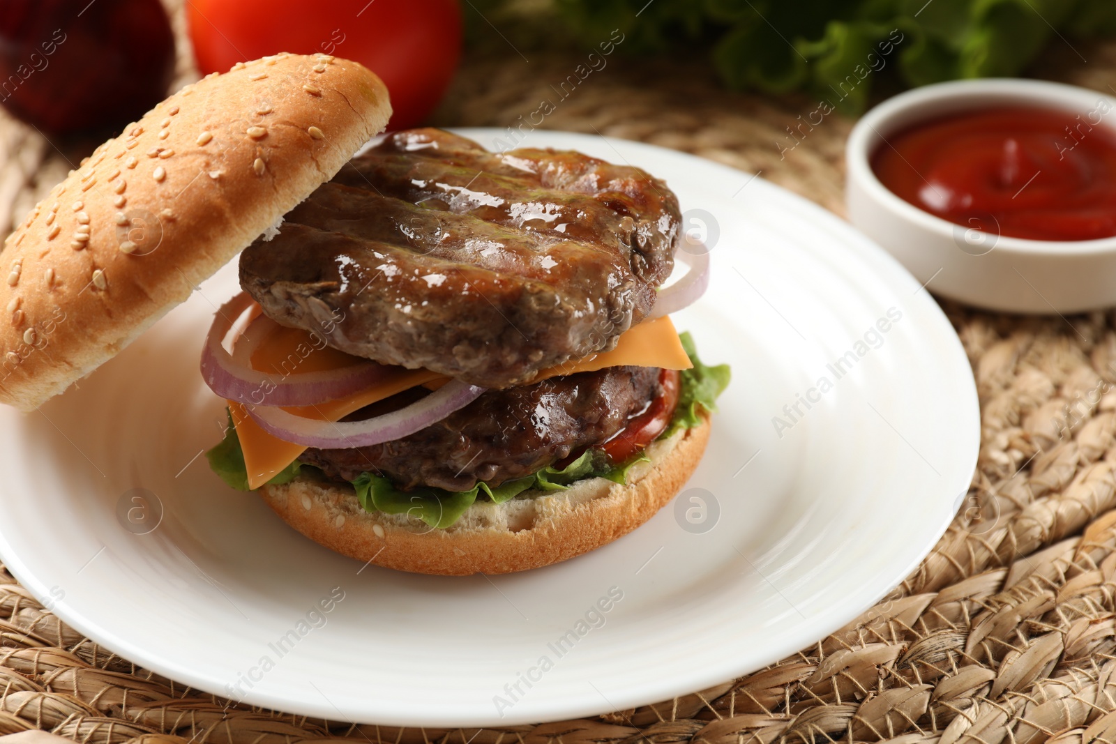 Photo of Tasty hamburger with patties, cheese and vegetables on wicker mat, closeup